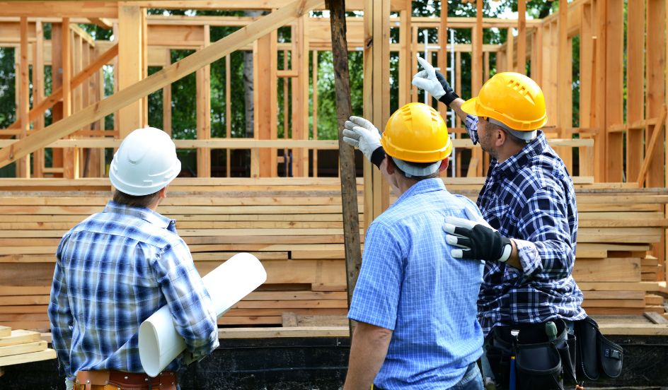 three construction workers standing in front of a wooden building structure