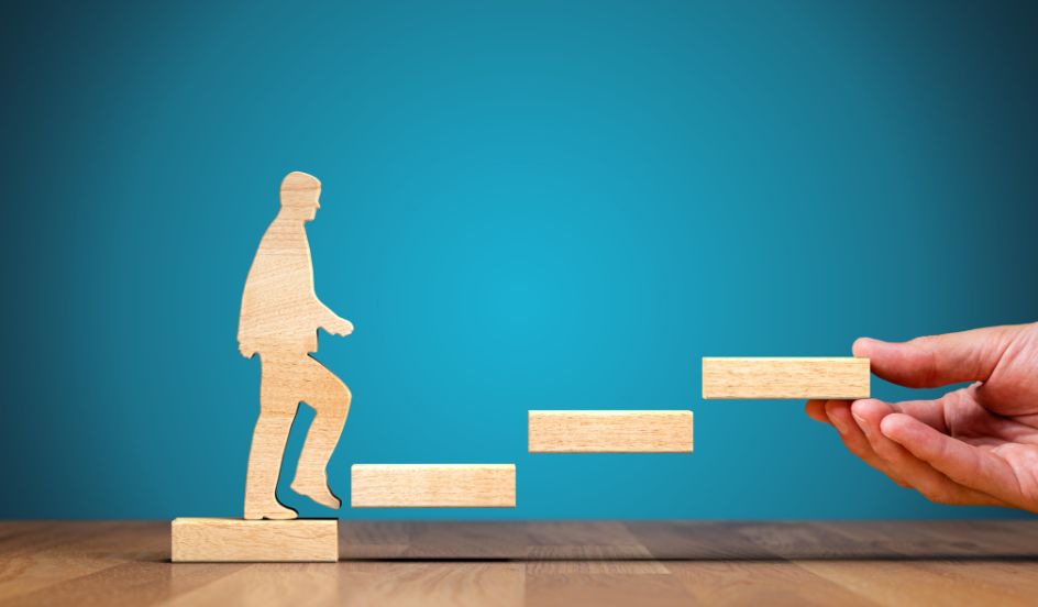 wooden figure of a man climbing wooden blocks moving up