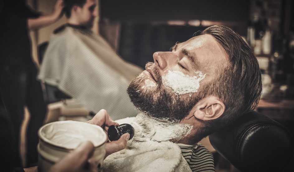 man receiving a straight razor cut at a barbershop 
