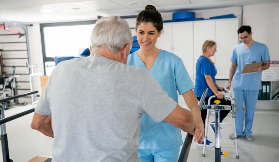 physiotherapist helping man walk 