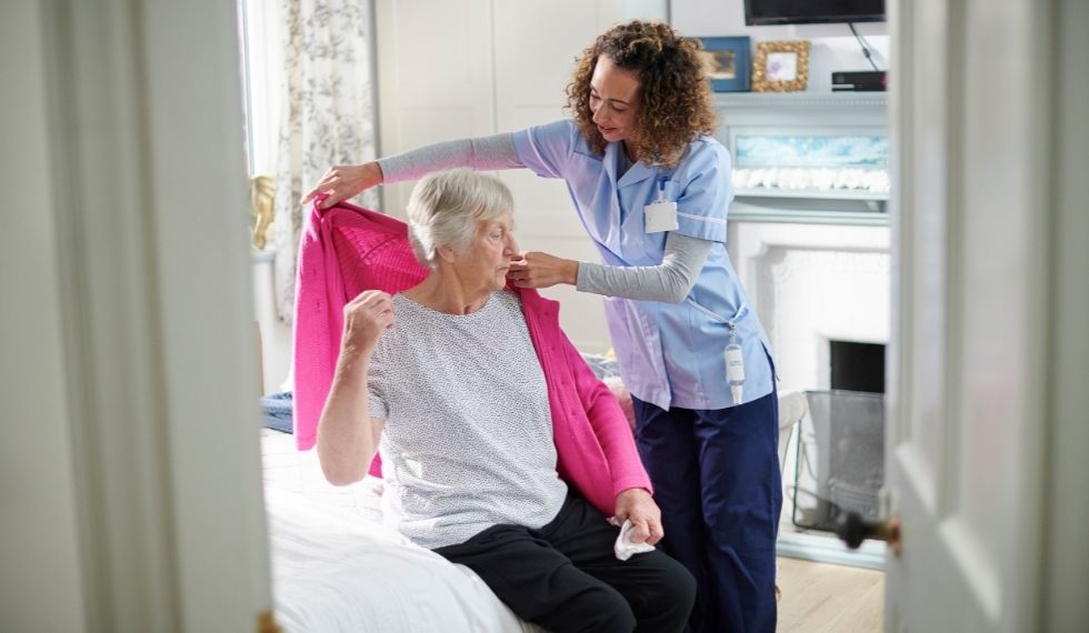 A continuing care assistant helps her client get dressed 