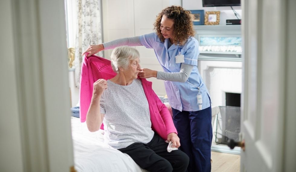 A continuing care assistant helps her client get dressed