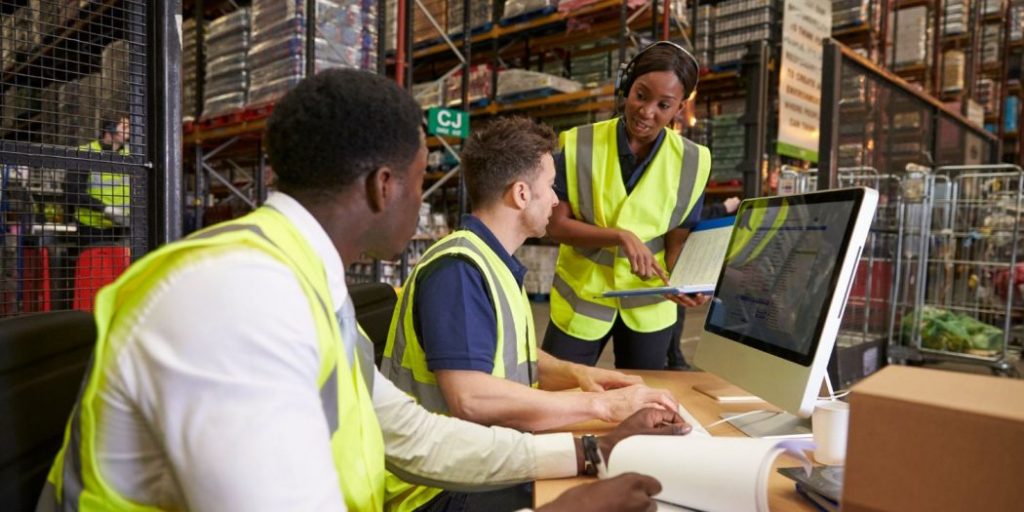 three supply chain management and logistics employees inside a warehouse